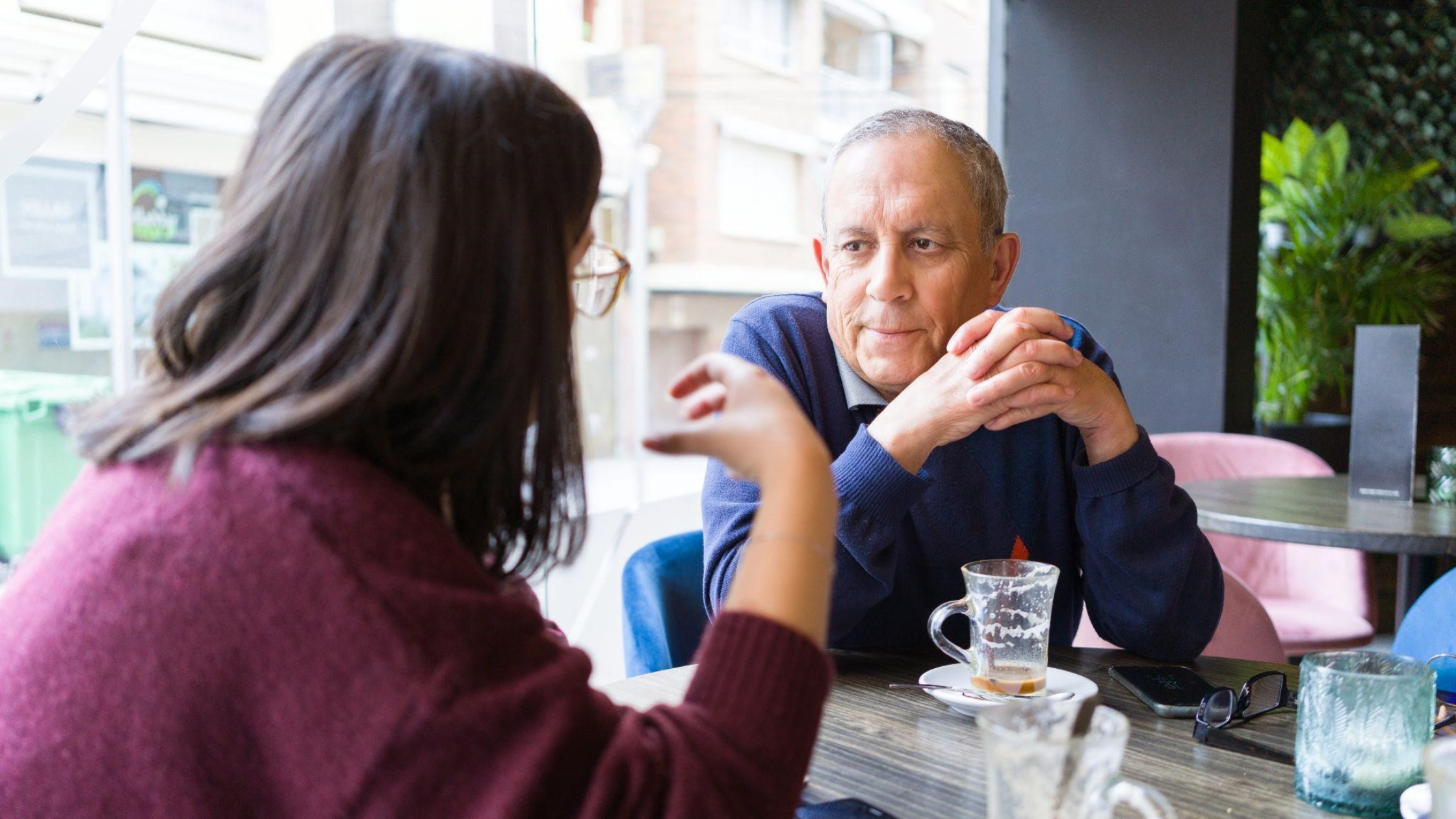 Senior man having a conversation with woman drinking coffee and relaxing, chatting at restaurant